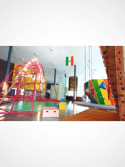 This panoramic view captures the layout of our climbing gym. You can see the relationship between the tall top-rope wall, the central bouldering area, and the iconic red arch, showcasing the scale and variety of our facility.