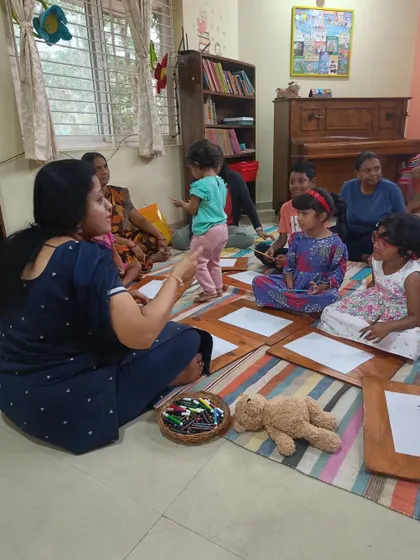 The storyteller interacts with the children during craft time, offering encouragement and help.