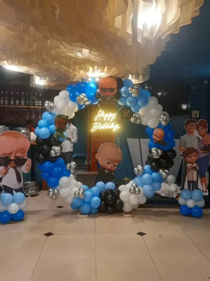 A Boss Baby themed balloon ring setup in a restaurant, surrounded by character cutouts on balloon stands for a fun photo opportunity.