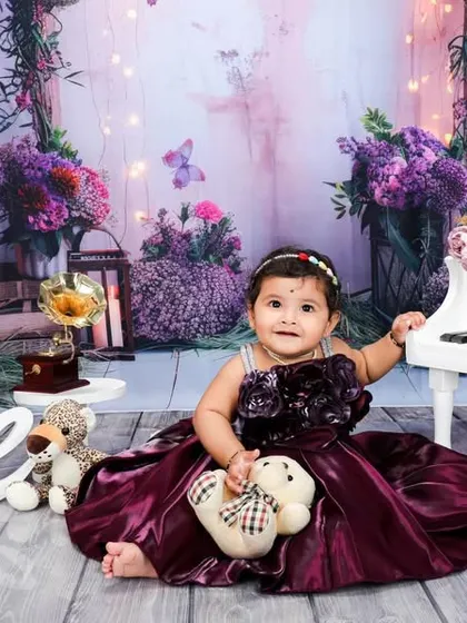 A wider view of the enchanting purple piano set. The soft lighting and fairytale-like background elements come together to create a truly memorable first birthday photograph.