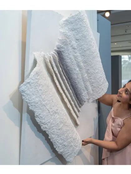 Adjusting "The Flight of Knowledge." The piece is made from upcycled paper, giving it a beautifully raw and textured feel, like the pages of an ancient book.