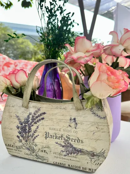 A charming centerpiece detail, featuring a vintage-style handbag used as a vase, adding a unique and fashionable touch to the table decor.