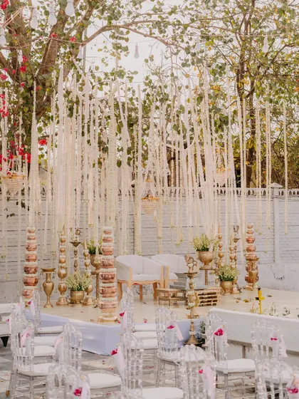 The beautiful wedding mandap, decorated with hanging white florals and traditional brass elements, ready for the ceremony.