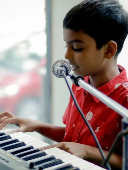 The future of music is bright. A young student confidently playing the keyboard and singing at a recital.