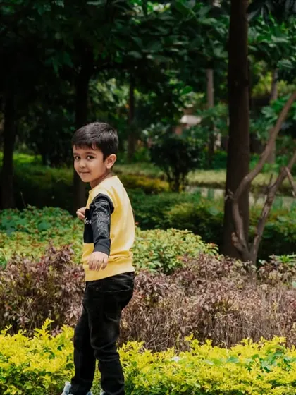 Capturing a child's playful energy as he looks back with a smile during our outdoor photoshoot in a lush Bangalore park.