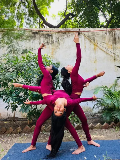 A beautiful three-person yoga pose creating a 'Triveni' or confluence, symbolizing unity and balance.