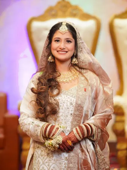 An elegant solo portrait of the bride from her Nikaah ceremony, showcasing her beautiful white and gold sharara, jewelry, and henna.