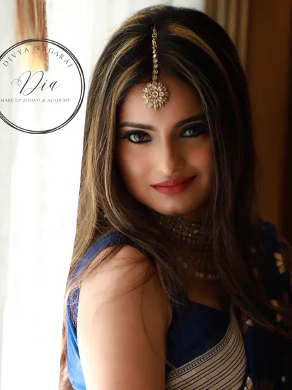 A direct and confident portrait showcasing the classy blue saree and smokey eye makeup. This look is for the bride who wants to make a bold statement at her reception. It's all about glamour and self-assurance.