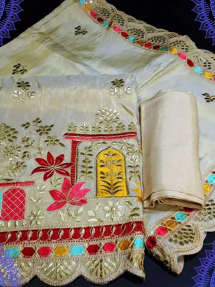 A festive unstitched dress material with beautiful, colorful embroidery depicting a traditional scene. The dupatta has a lovely scalloped border with multi-colored details, making it a truly unique piece.