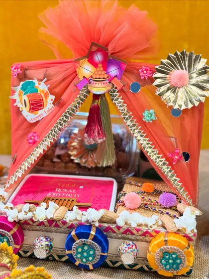 This beautiful Lohri hamper is decorated like a canopy tent. It's filled with dry fruits and traditional sweets, making it a delightful and elegant gift.