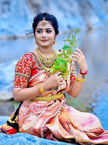 A bride looking serene and beautiful in a custom red and cream saree with a heavily embroidered blouse.
