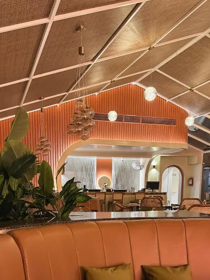 A look towards the bar area, framed by lush greenery. The design uses fluted textures and arched forms to create a cohesive and sophisticated look.