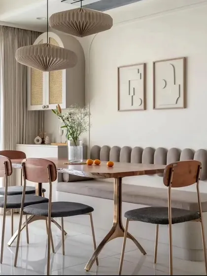 This dining space features a comfortable banquette with a fluted backrest and sculptural paper pendant lights. The design is a perfect blend of style, comfort, and modern artistry.