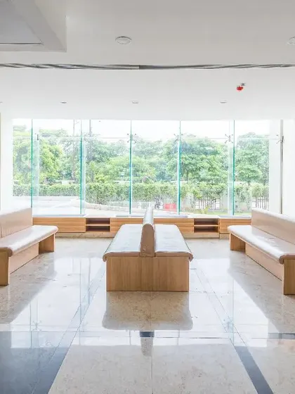This waiting area at a repurposed facility uses simple, modern furniture and large windows with views of greenery. The design integrates nature into the space, breathing life into what could be an uninspiring hospital environment.