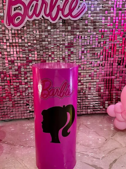 A close-up of a custom-branded pedestal with the iconic Barbie silhouette, used as part of the themed decor.