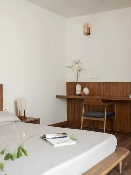 This bedroom from the Earthen Anthem penthouse follows a Japandi-inspired design, with a calm, warm, and functional aesthetic combining wood and white walls.