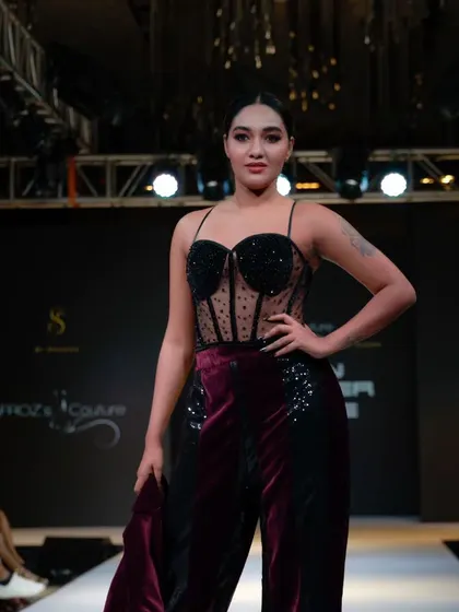 A model showcasing a burgundy and black couture outfit, demonstrating the variety of styles within a single show.