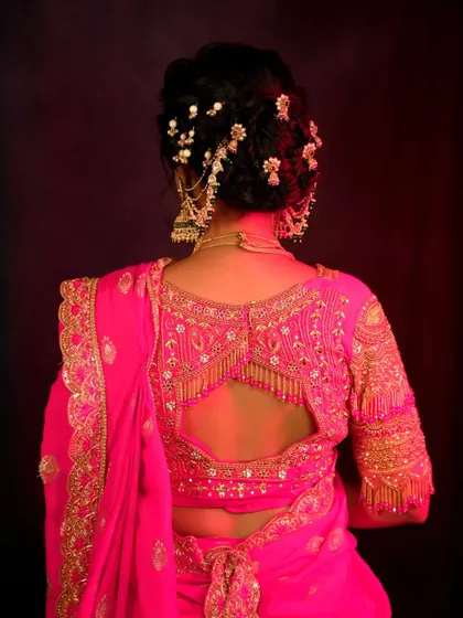 A detailed shot of the bride's intricately embroidered blouse and traditional hair accessory. This image highlights the craftsmanship and beauty of the bridal attire.