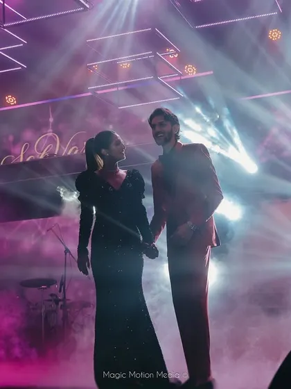 A romantic shot of the couple on stage, surrounded by dramatic concert-style lighting.