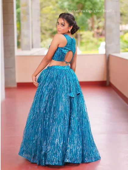 The back view of a sparkling teal blue lehenga, featuring a stylish halter neck and keyhole cutout.