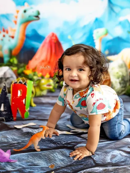 Crawling through a prehistoric landscape, this happy baby is having a blast during his dinosaur-themed first birthday session.