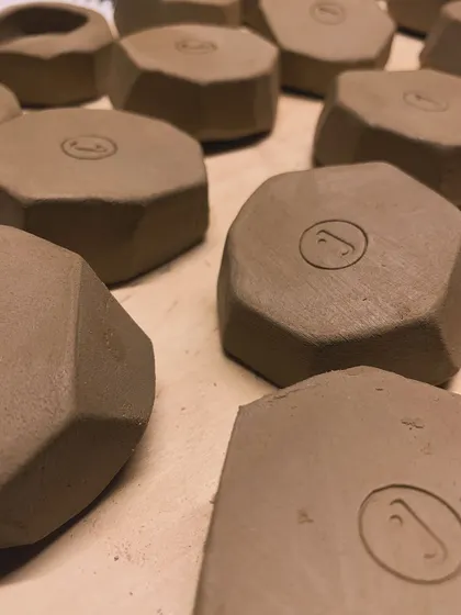 A collection of geometric, faceted pieces, each stamped with my logo. This is a glimpse of a new collection in the making, seen here in its raw, unglazed form.