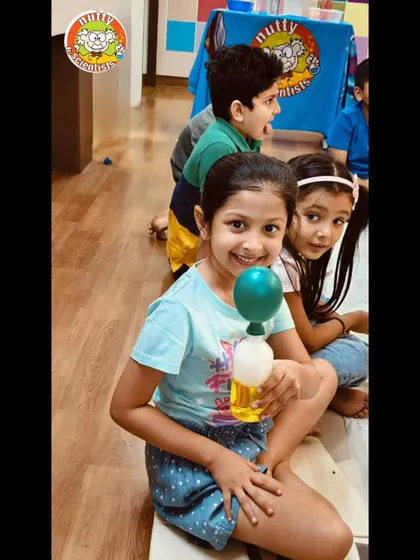The pure joy of a successful experiment! This girl's smile captures the excitement of watching her chemical reaction inflate a balloon all by itself.