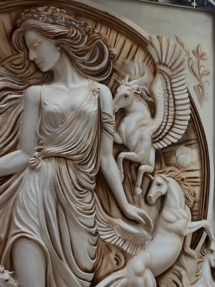 A close-up on the serene face of the goddess and the mythical winged horse, Pegasus. The delicate carving captures a sense of grace and power.