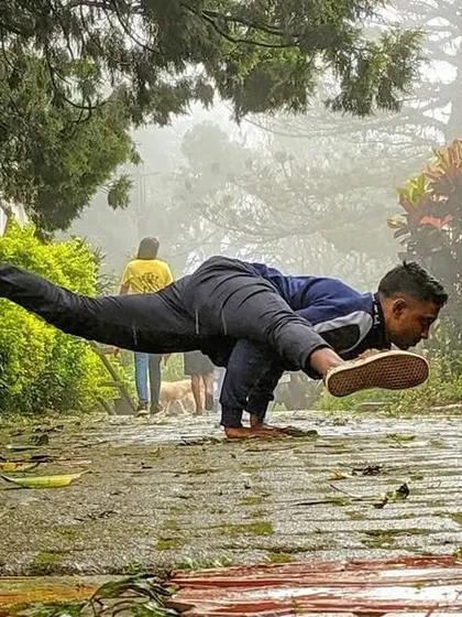 Koundinyasana B on a wet, leafy path. The uneven surface adds an extra challenge to the balance, forcing the mind to be fully present.