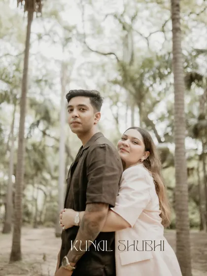 A tender moment of a woman hugging her partner from behind in a forest setting. The soft light and natural background create a serene and romantic mood.