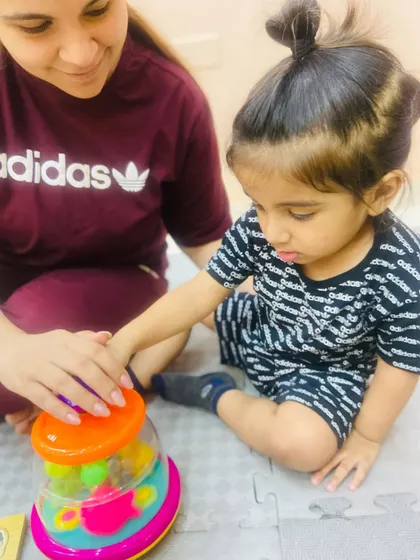 A close-up of a mother and child playing with a colorful spinning toy, sharing a moment of discovery.