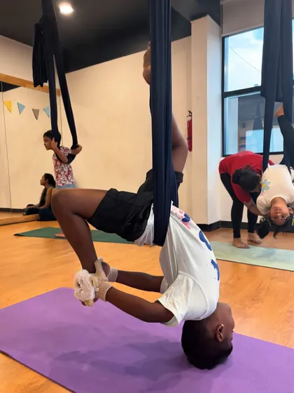 An instructor helps a young student with an inverted aerial pose. Safety is our top priority, and we provide hands-on guidance to ensure every child feels secure.