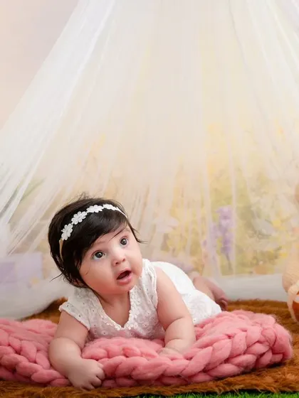 A precious tummy-time portrait of a four-month-old baby girl, looking up with wonder and curiosity.