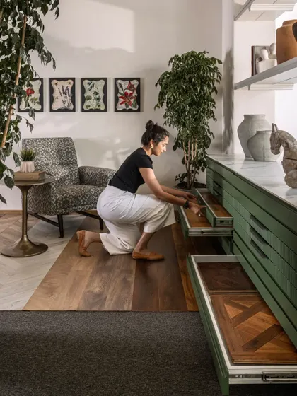 Here, I am demonstrating the custom-designed storage for flooring samples. The sleek green drawers house various samples, allowing them to be displayed easily without cluttering the main showroom floor. This is smart, integrated design in action.