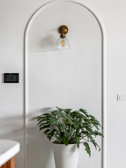 A close-up of the simple wall arch, accented with a classic wall sconce and a planter. Sometimes the most beautiful designs are the most simple.