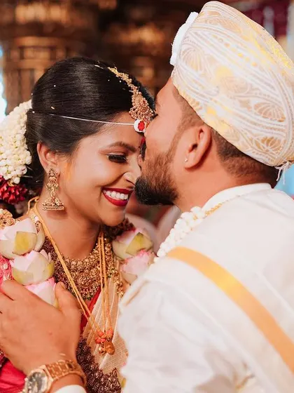 A tender kiss on the forehead, a gesture of love and protection amidst the wedding celebrations. This candid moment captures the deep affection between the couple.