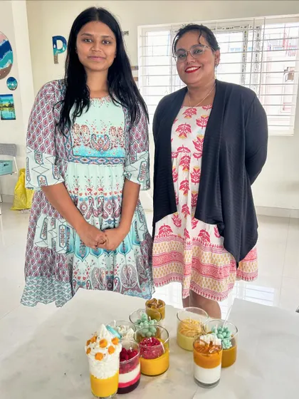 Two friends proudly displaying the mango and other fruit-themed dessert candles they made.