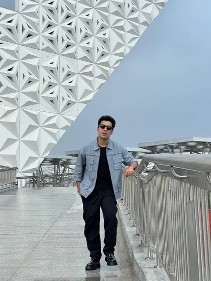 Gagan Arora at the Vivo launch event, styled in a monochromatic look with a statement jacket from Blamblack Clothing against a futuristic architectural background.