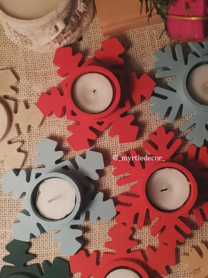 An overhead view of our red and blue Snowflake T-light holders. We love how the colors pop against the rustic burlap, showcasing their simple yet festive design.