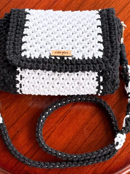 A beautifully styled shot of the black and white floral strap sling bag on a wooden table.