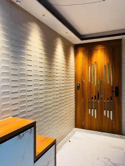 For this entrance, I used 3D wall panels with a chevron pattern to create a textured accent wall, complemented by a modern wooden door.