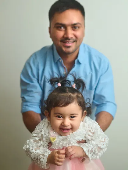 Even a simple indoor setup can create a beautiful family portrait. This photo captures a sweet, happy moment between a father and his little girl against a clean, neutral background.
