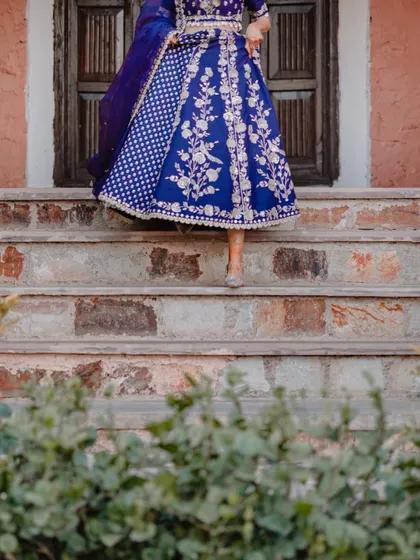 A low-angle shot of the bride Leesha in her vibrant blue Mehendi lehenga, capturing the intricate details of the skirt.