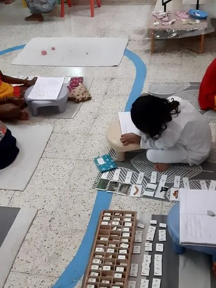 Here you can see the 'buzz' of a productive Montessori classroom. Children are engaged in various activities, some individually and some in small groups, all learning at their own pace in a calm, focused atmosphere.