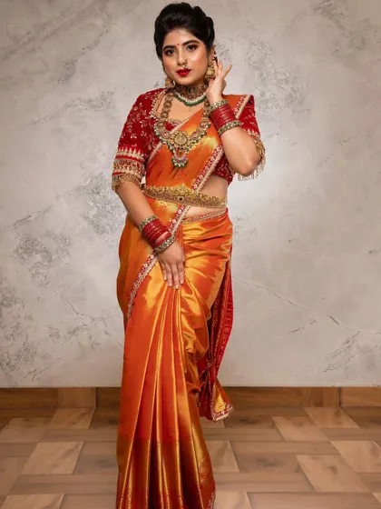 A full-length view of Shilpa's stunning traditional look. The makeup is balanced to complement her vibrant orange and red saree, creating a cohesive and beautiful bridal image.