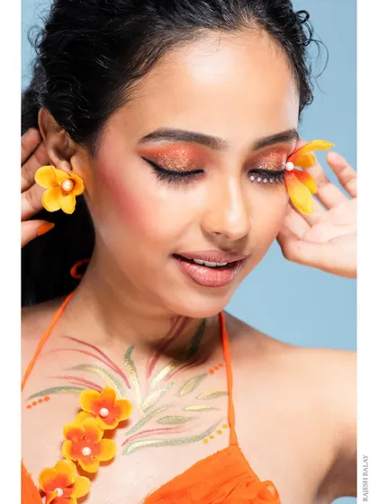 A close-up of the model, showing the details of the floral makeup and her happy expression.