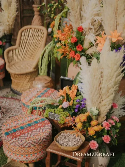 A close-up of the Moroccan-themed decor, showcasing a mix of textures from patterned poufs, a rattan chair, and arrangements of pampas grass and orange lilies.