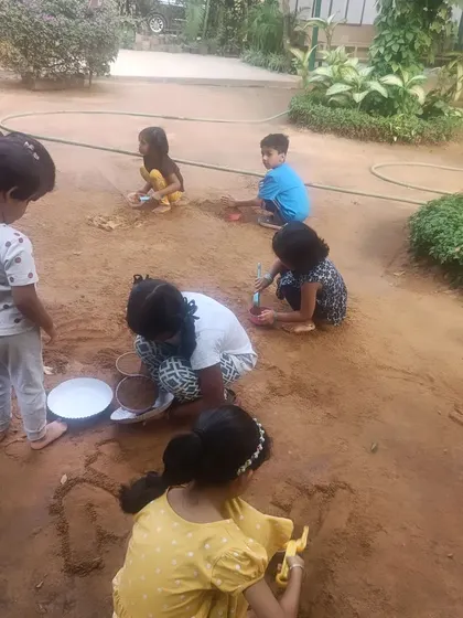 A duplicate of image 10, showing the full group enjoying the outdoor mud play area.