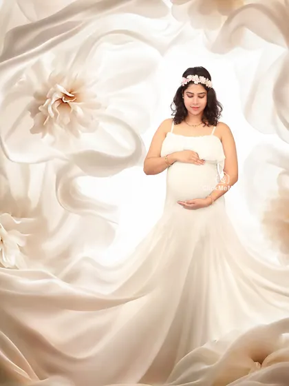 Surrounded by ethereal white blooms. This portrait uses a backdrop of soft, flowing fabric and delicate flowers to create a heavenly and pure look for the mom-to-be.