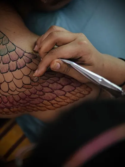 An action shot of me meticulously applying the colored henna for the mermaid scale body art piece during our collaborative photoshoot.